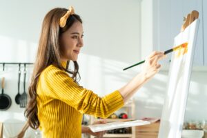 Asian young talented woman artist coloring on painting board during classes.